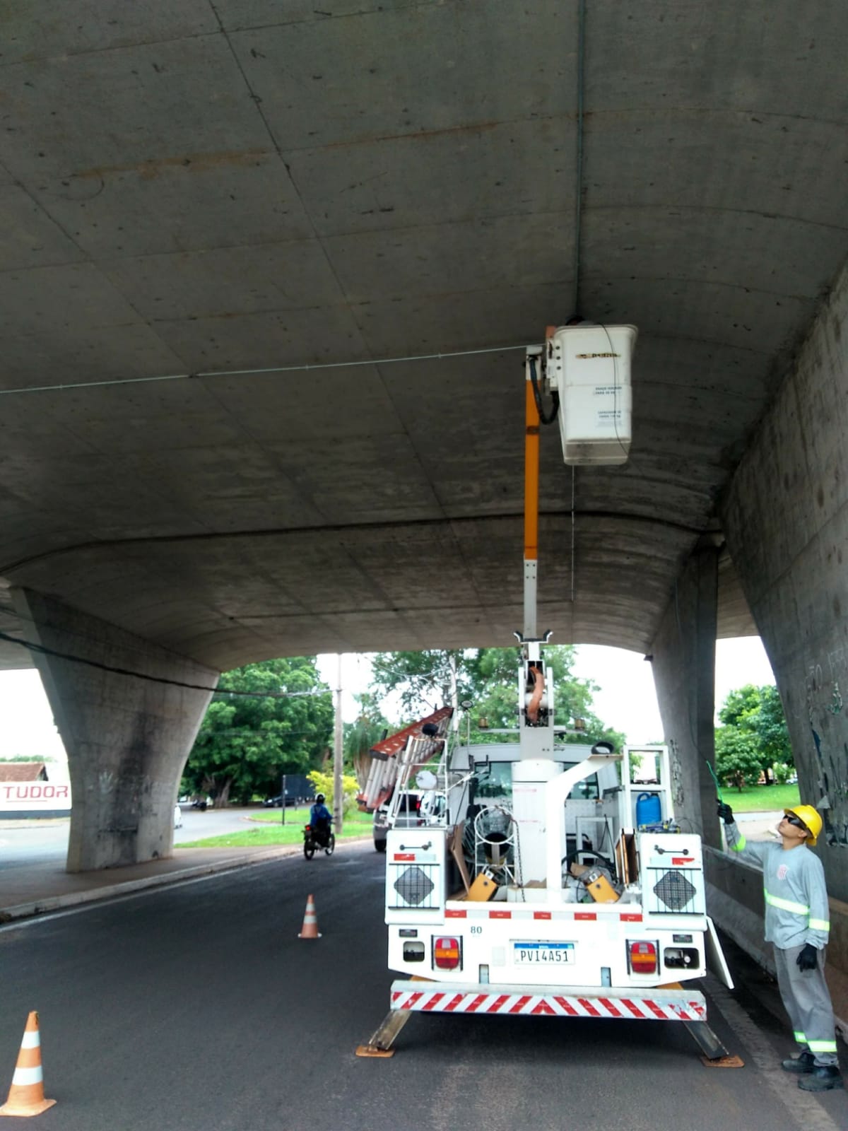 Caminhão com cesto aéreo em manutenção elétrica sob viaduto